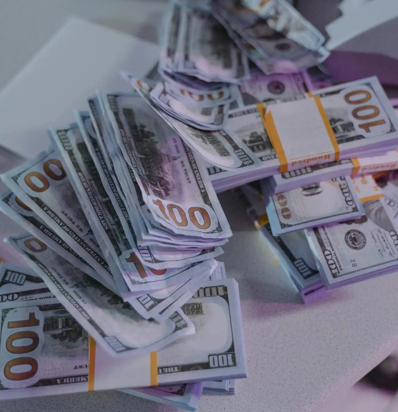 A substantial pile of one hundred dollar bills representing financial freedom