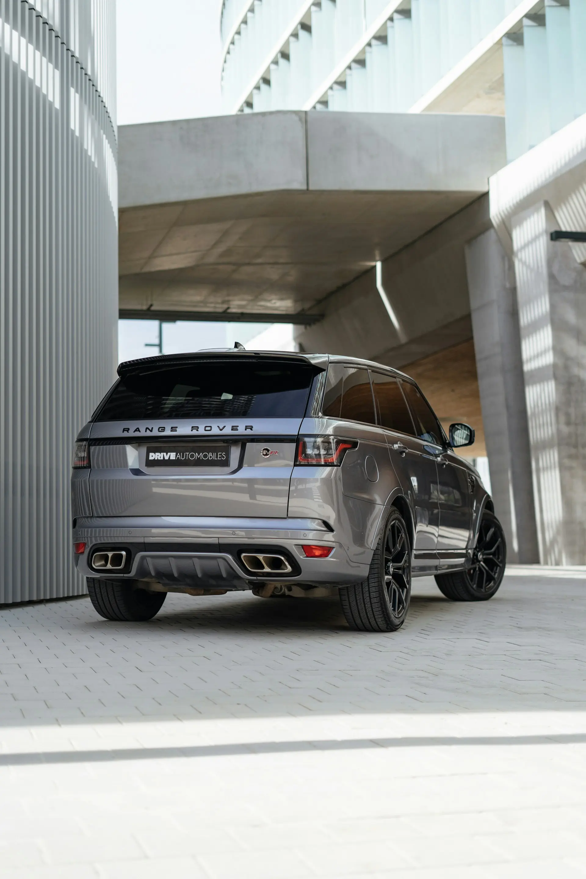 A grey Range Rover SUV parked in front of a modern building